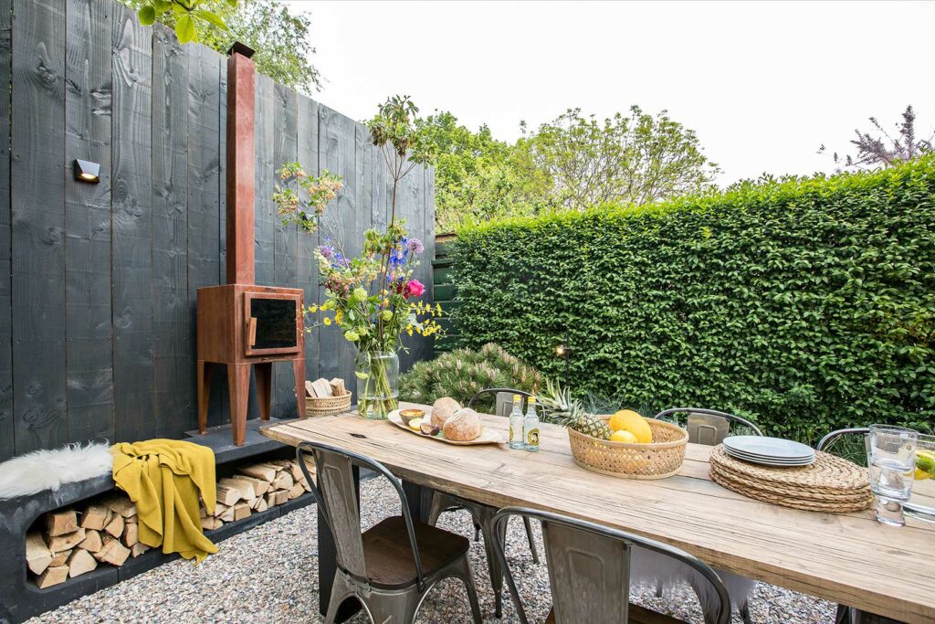 Präsentation eines Gartentisches aus Waggonbohlen mit Eisenofen und Stühlen