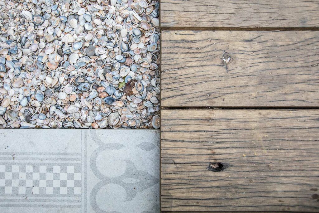 Detail photo of outdoor decking of planed oak wagon planks next to stone and shell covering