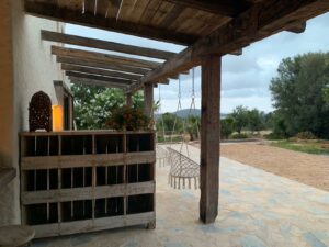 Presentatie van oud eiken balken in veranda op Ibiza met hangstoelen