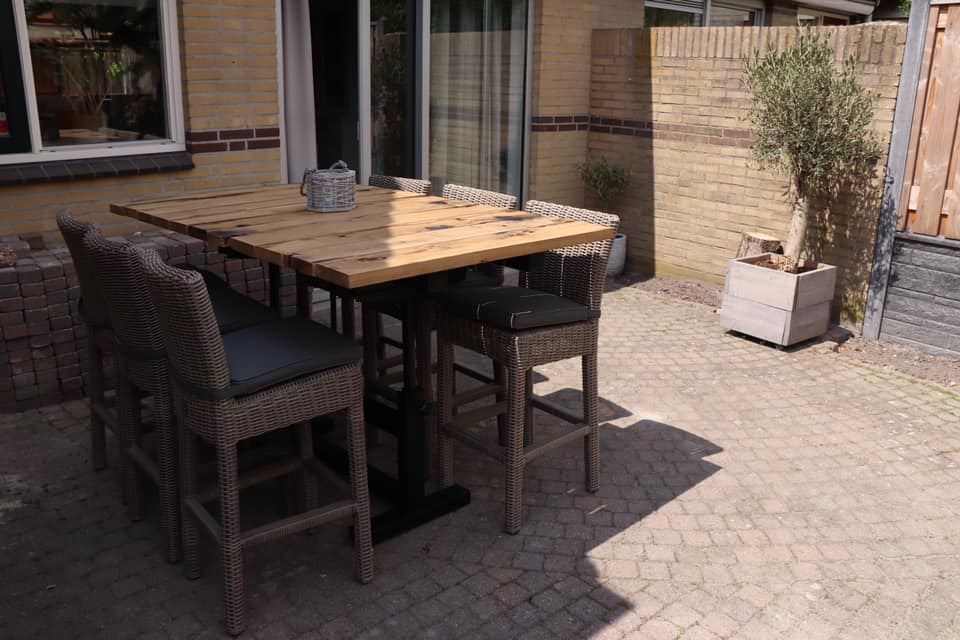 Outdoor table made of oak wagon planks with chairs in backyard