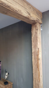 Präsentation verschiedener Eichenbalken im Haus neben einer grauen Wand