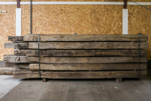 Presentatie van een pak oude eiken balken in oud hout loods