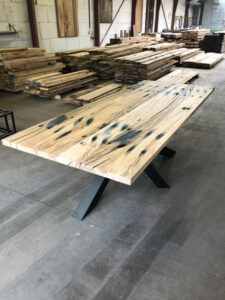 Presentation of a table of planed oak railroad sleepers with black steel cross leg and drawing in old wood shed