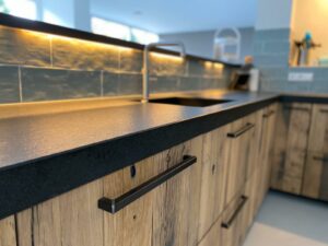 Presentation of kitchen made of old oak wagon parts with black kitchen top and handles