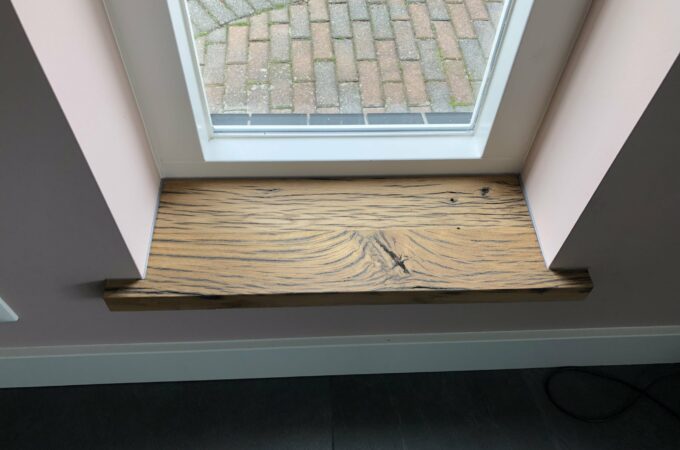 Window sill of oak wagon planks in white frame