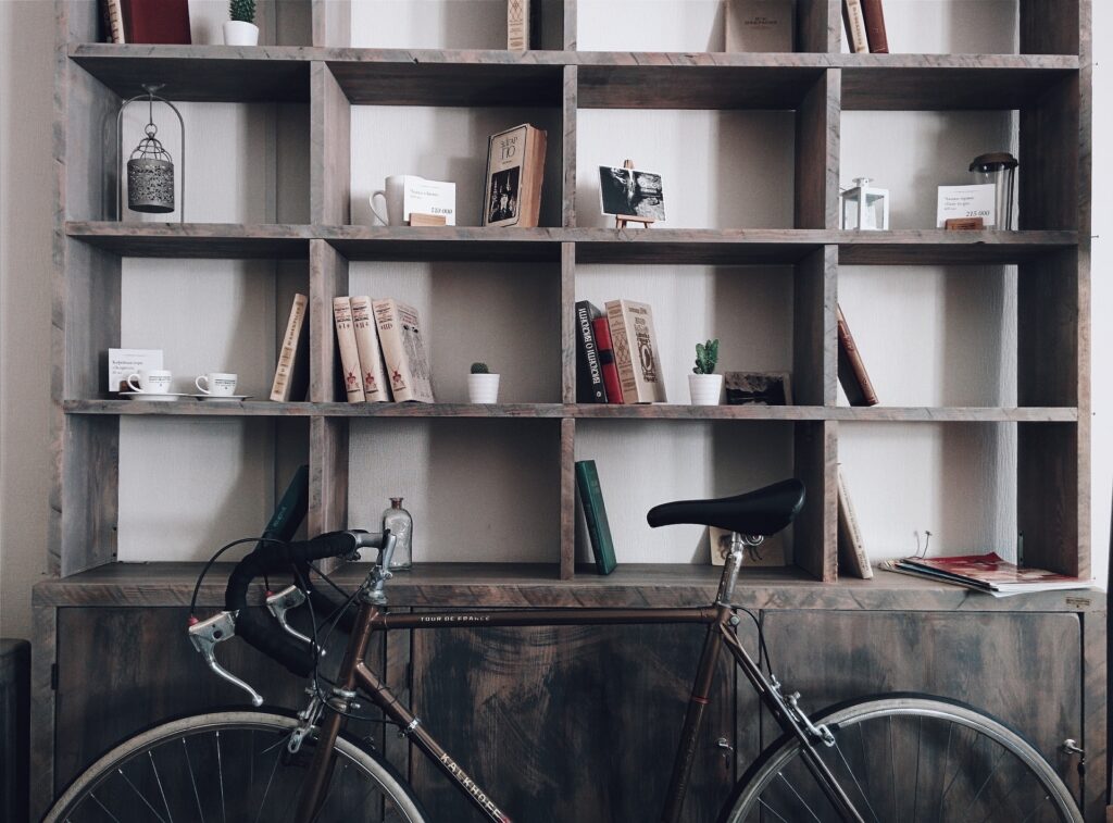 Presentatie van een vakkenkast van oud eiken met fiets ervoor